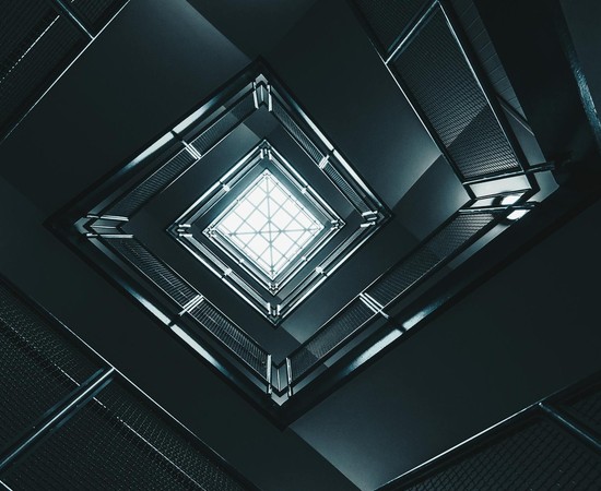 Abstract view of a geometric building interior looking up towards the sky, emphasizing modern architecture.